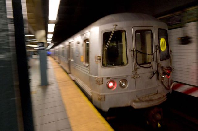A W train pulls into Times Square in a blurry shot depicting motion.